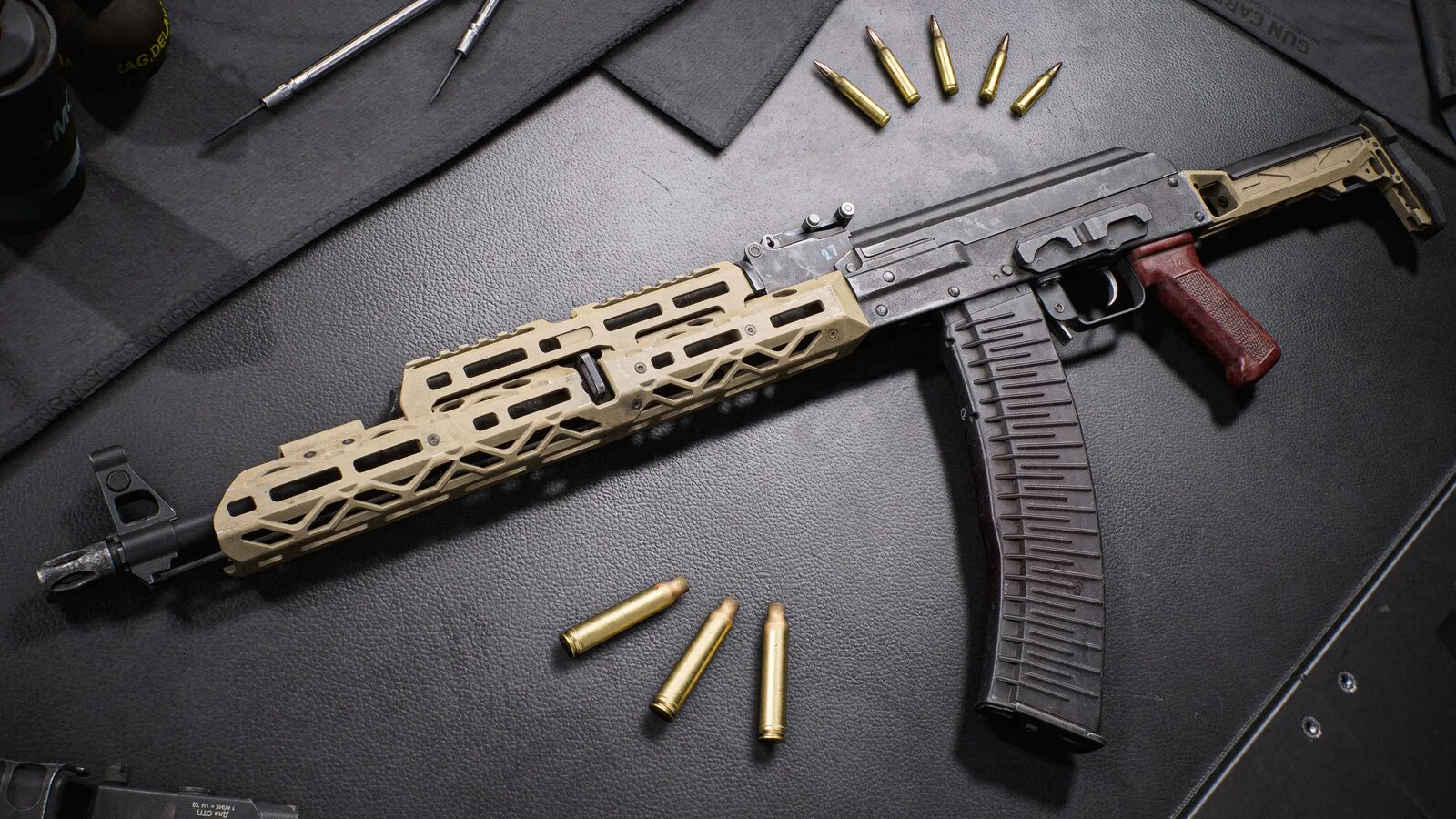 The RPK-74M light machine gun with a tan handguard and long curved magazine on a dark workbench with loose cartridges