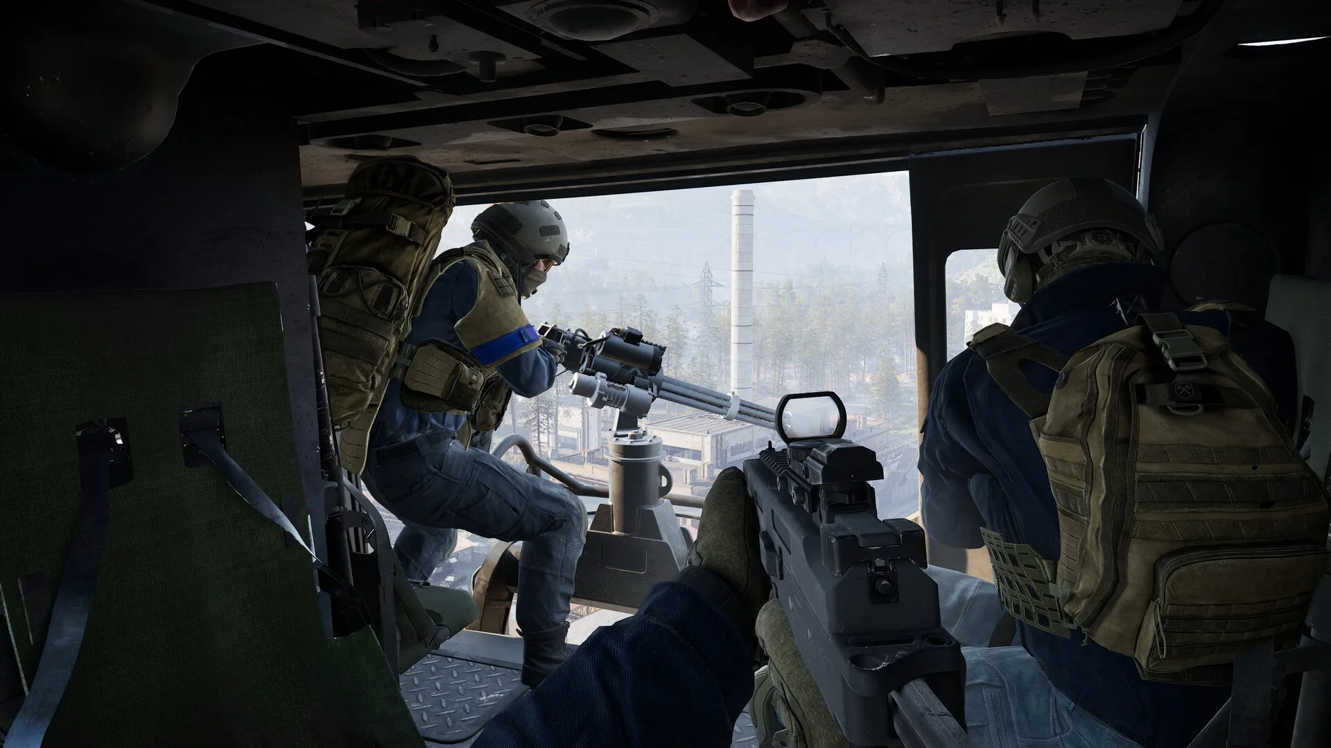 View from inside a WARDOGS transport helicopter: a door gunner on a minigun and a second soldier looking out over a valley with a chimney and pylons