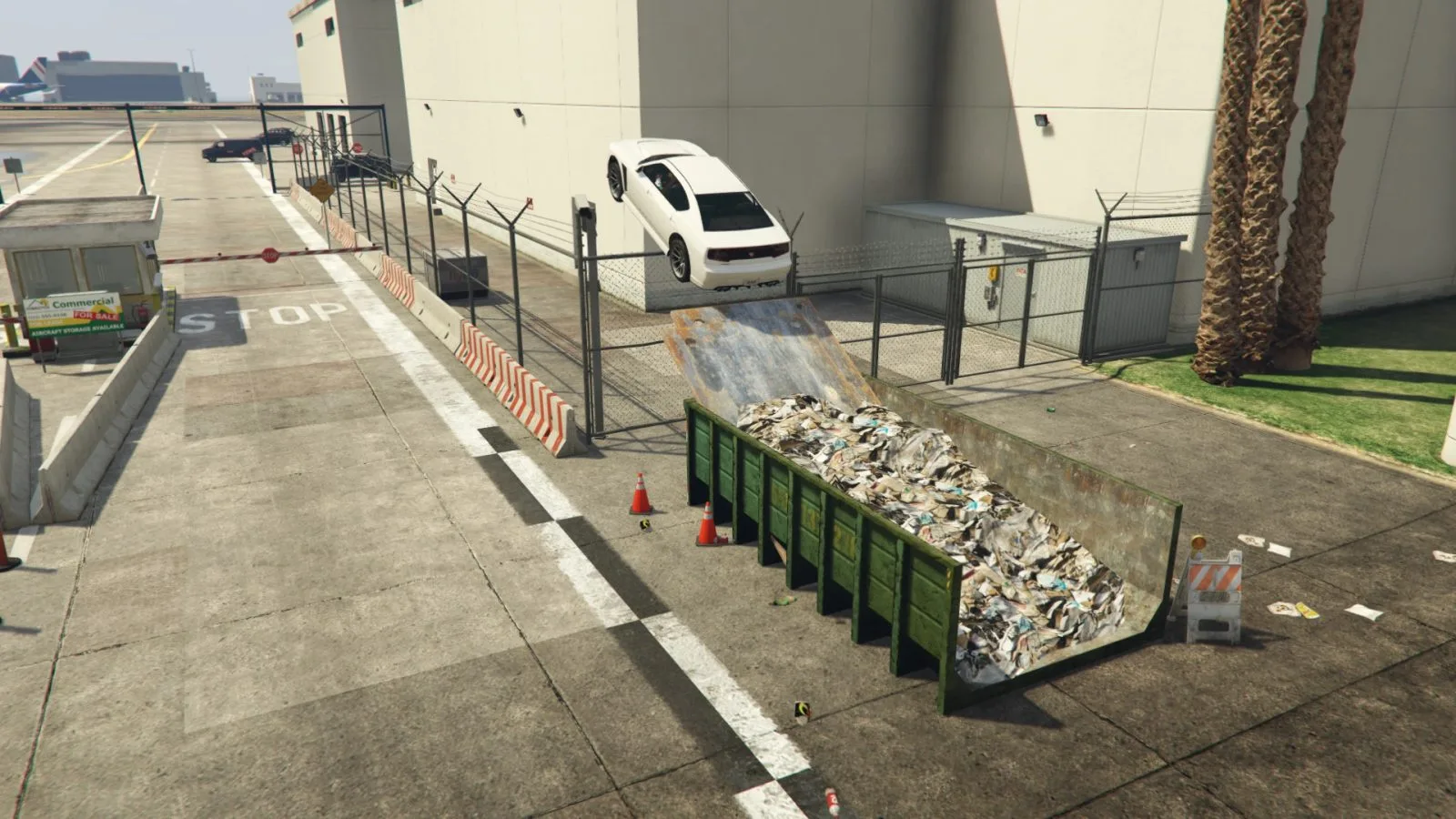 A white car flying off a ramp over a skip at the Los Santos International Airport entrance, the first Unique Stunt Jump