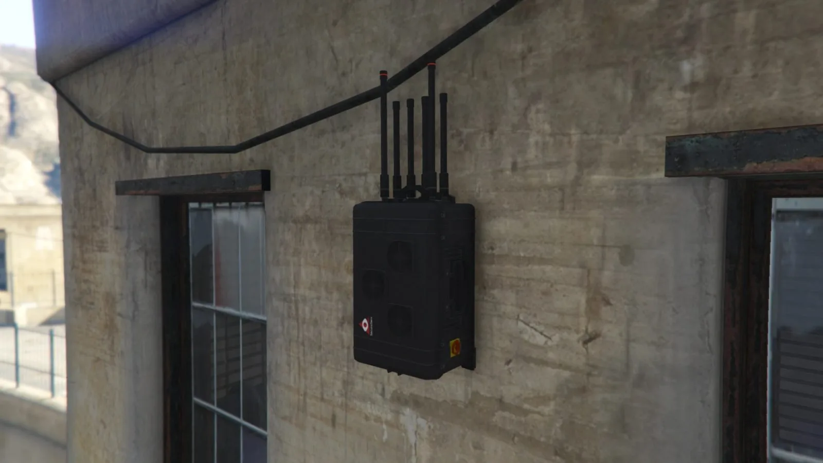 A black signal jammer with antennas mounted on a concrete wall