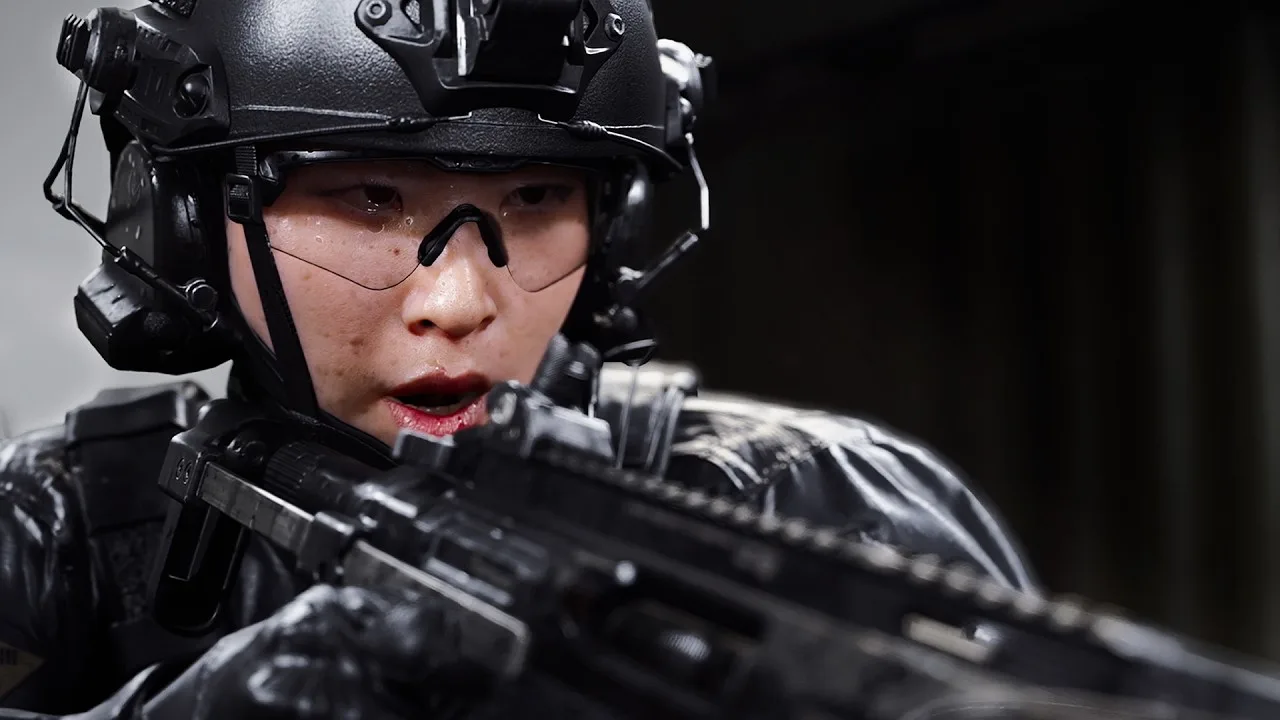 Close-up of a Modern Warfare 4 operator in a black helmet, headset and clear glasses aiming a rifle, from the official PC trailer